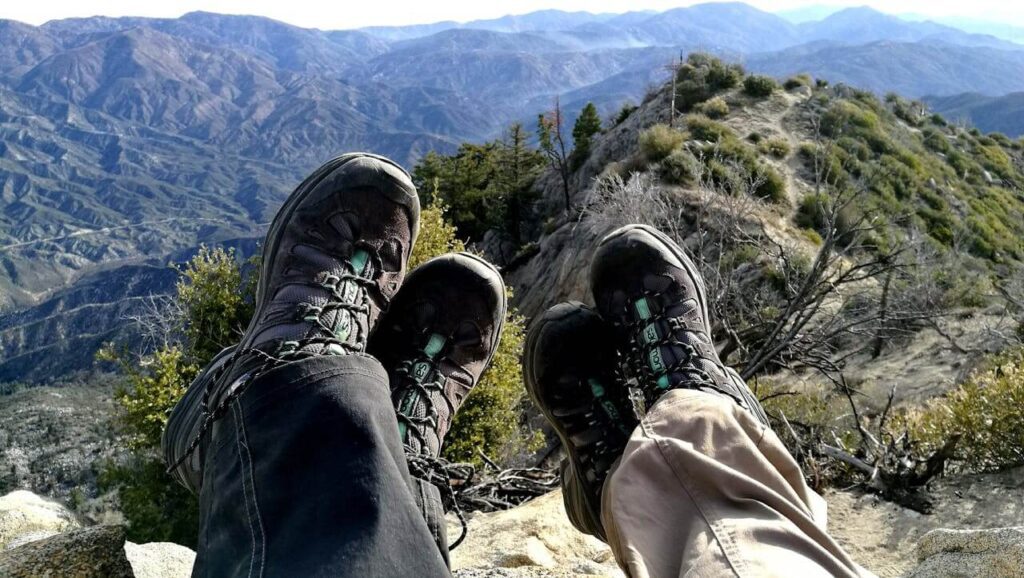 Hiker wearing protective hiking boots on rocky Arizona desert trail to prevent snake bites